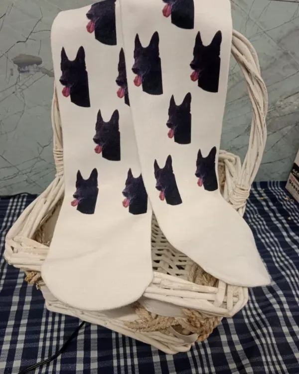 Calcetines blancos con caras de gato negras y orejas rosas cubriendo una silla de mimbre con un paño de cuadros azules .