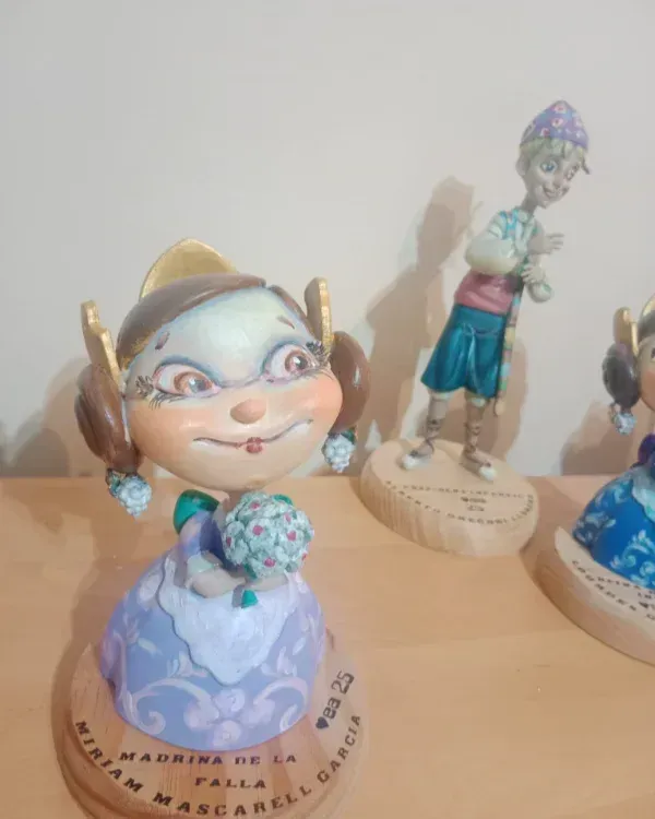 Pequeñas figuritas en un estante, incluyendo un personaje sonriente vestido de azul en primer plano.