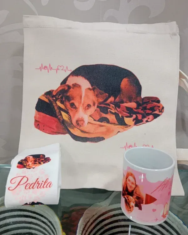 Bolsa blanca, taza y objeto doblado con estampado de perro sobre fondo gris.