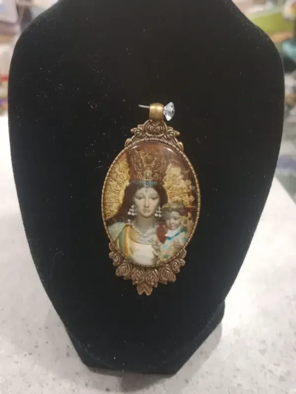 Patuco de bebé azul con estampado floral y cordones, colocado sobre una pequeña caja rosa con un fondo de tela oscura.