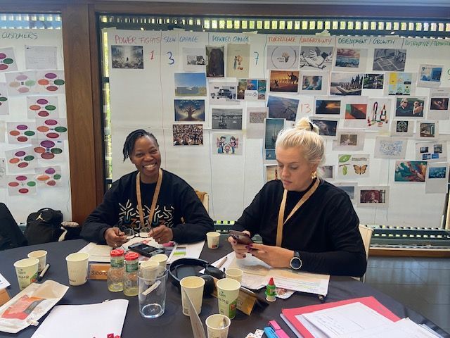 Dos mujeres están sentadas en una mesa mirando sus teléfonos.