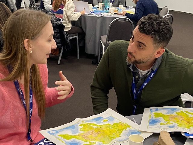Un hombre y una mujer están sentados en una mesa mirando un mapa.