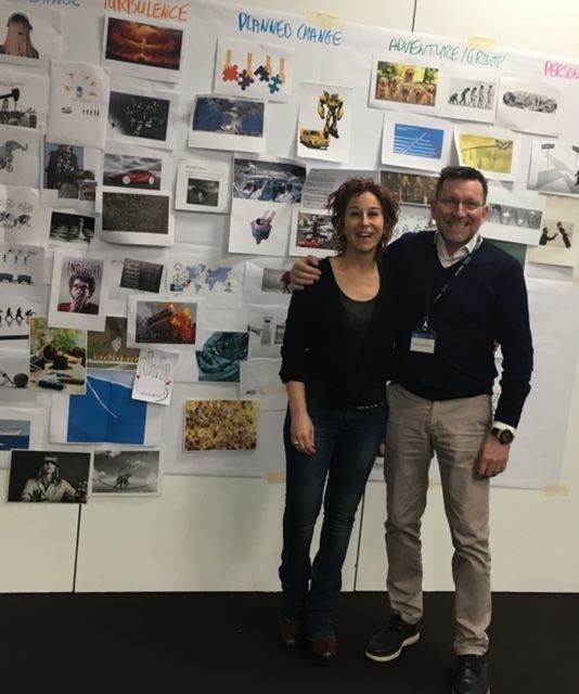 Un hombre y una mujer de pie frente a una pared con imágenes.