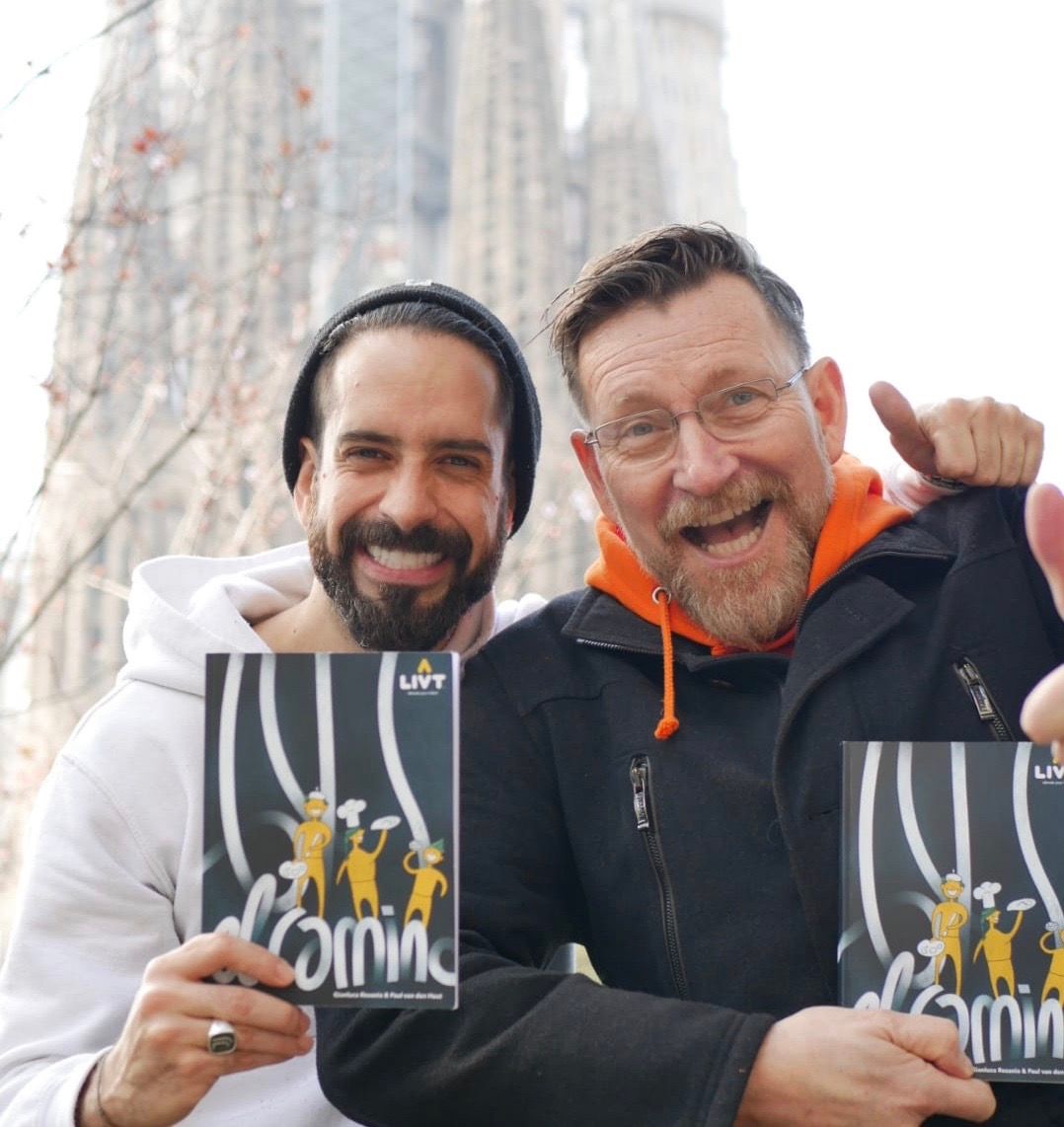 Dos hombres posan para una fotografía y uno sostiene un libro que dice 