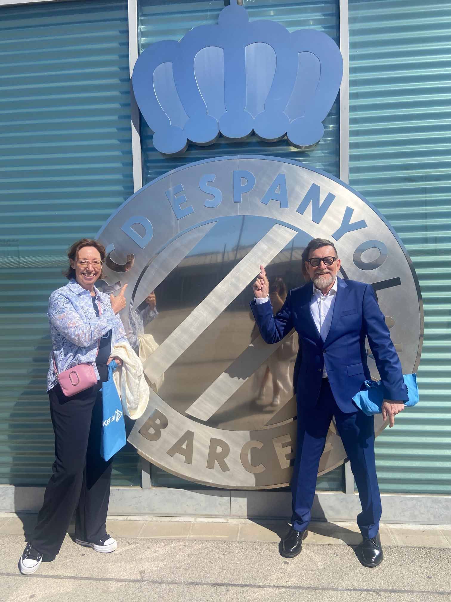 Un hombre y una mujer están parados frente a un gran cartel.