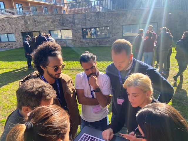Un grupo de personas están de pie alrededor de una mesa mirando una computadora portátil.