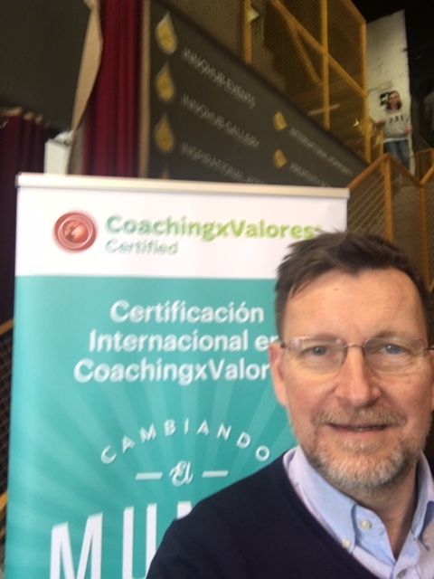 Un hombre se encuentra frente a un cartel que dice coaching x valores