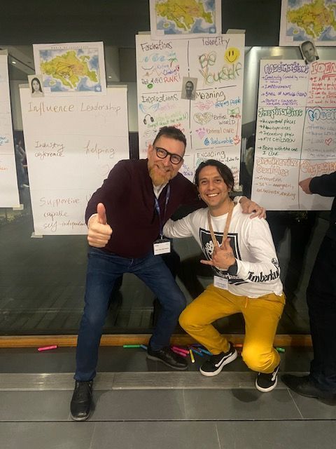 Dos hombres posan para una fotografía delante de una pizarra.