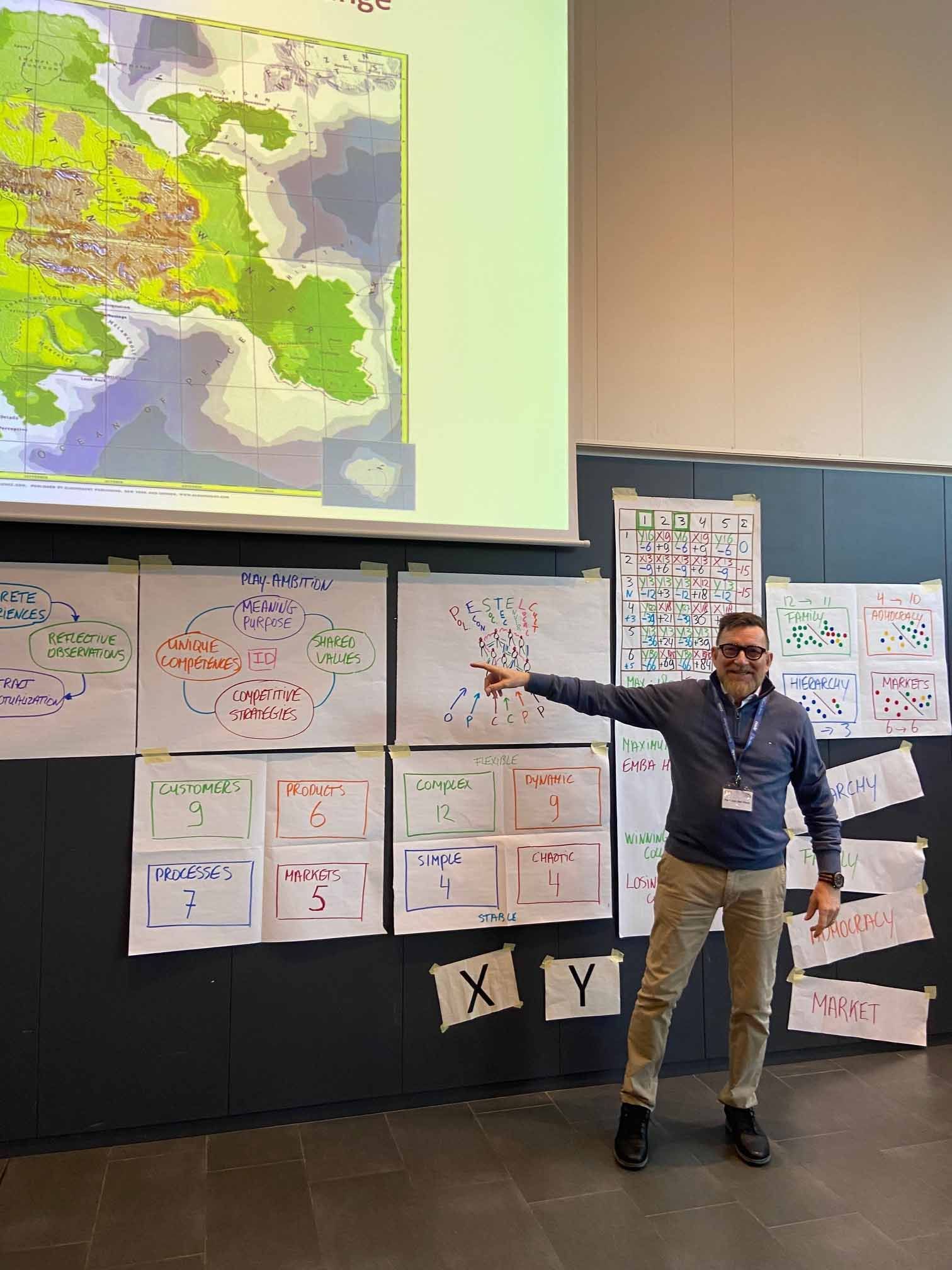 Un hombre está parado frente a una pantalla grande dando una presentación.