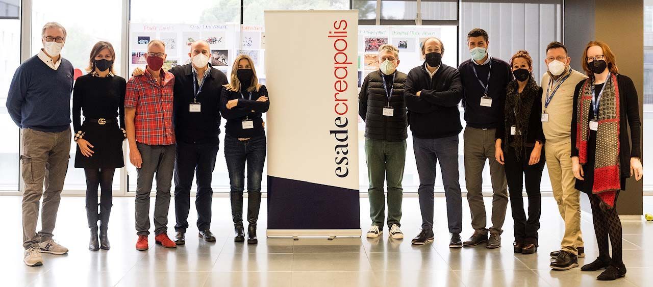 Un grupo de personas con máscaras posan para una foto frente a un cartel.