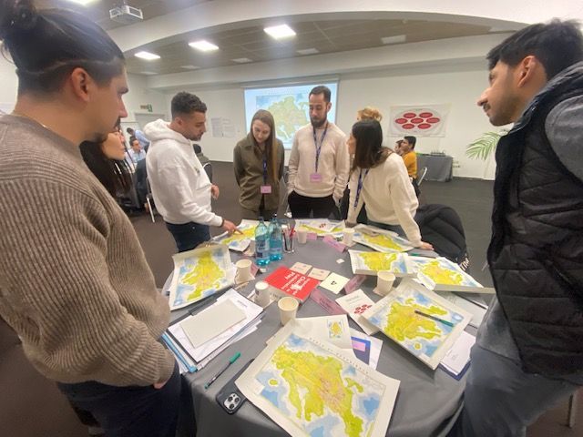 Un grupo de personas está de pie alrededor de una mesa con mapas sobre ella.