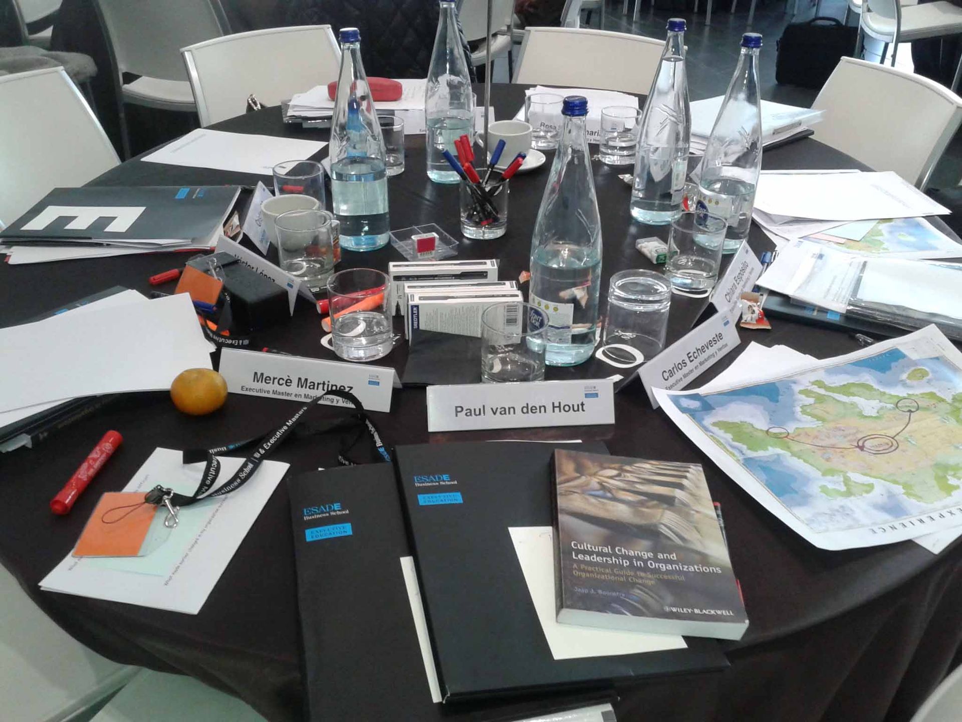 Una mesa redonda con botellas de agua y papeles encima.