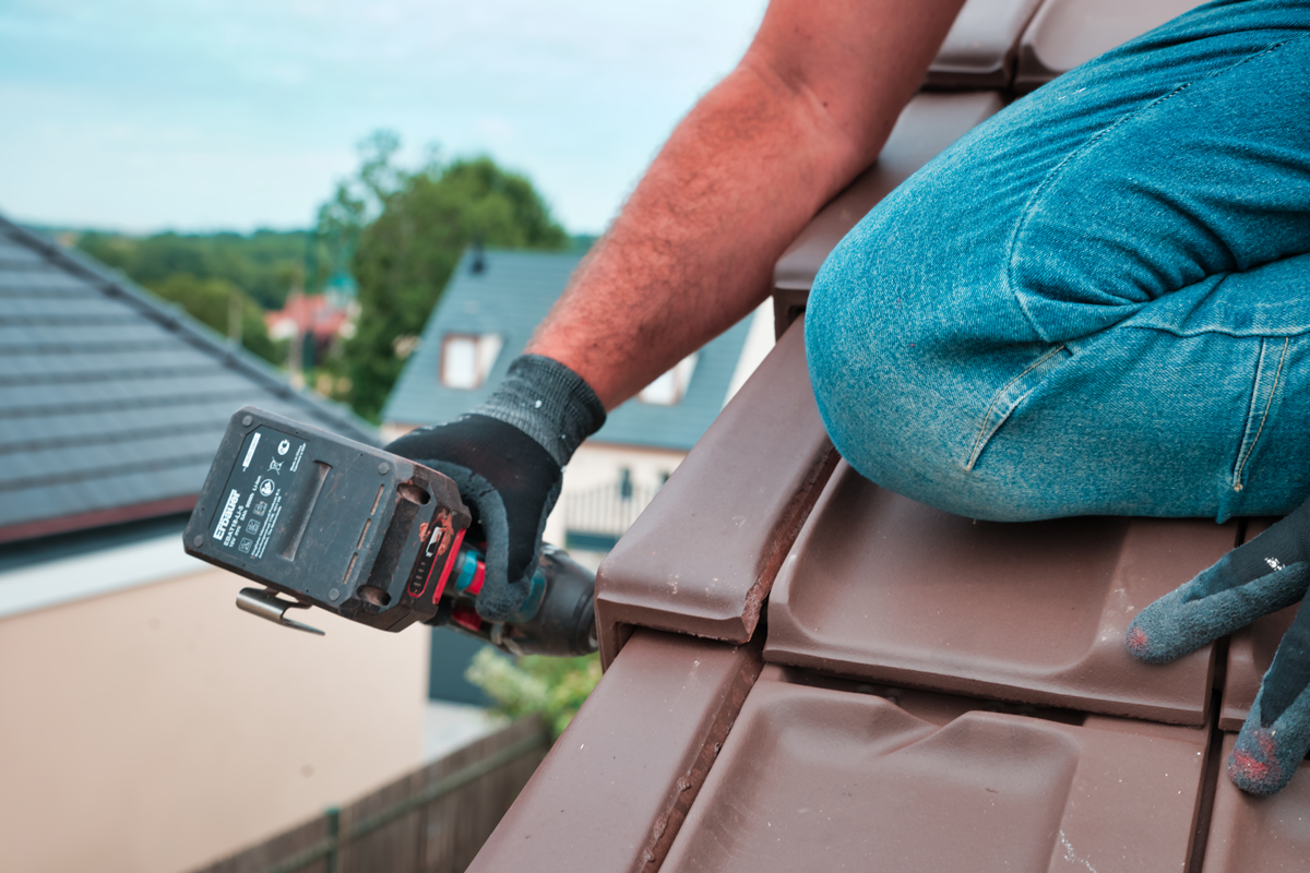 Professionnel avec une visseuse sur un toit