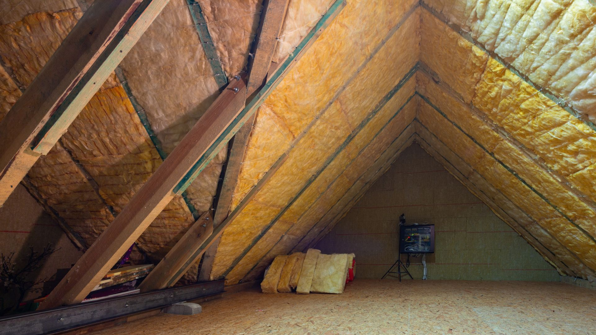 Intérieur du grenier avec isolation en laine de verre entre chevrons en bois.