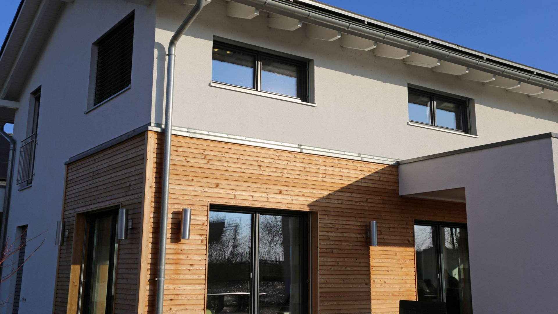 Une façade extérieure d'une maison avec une partie faite en bardage en bois.