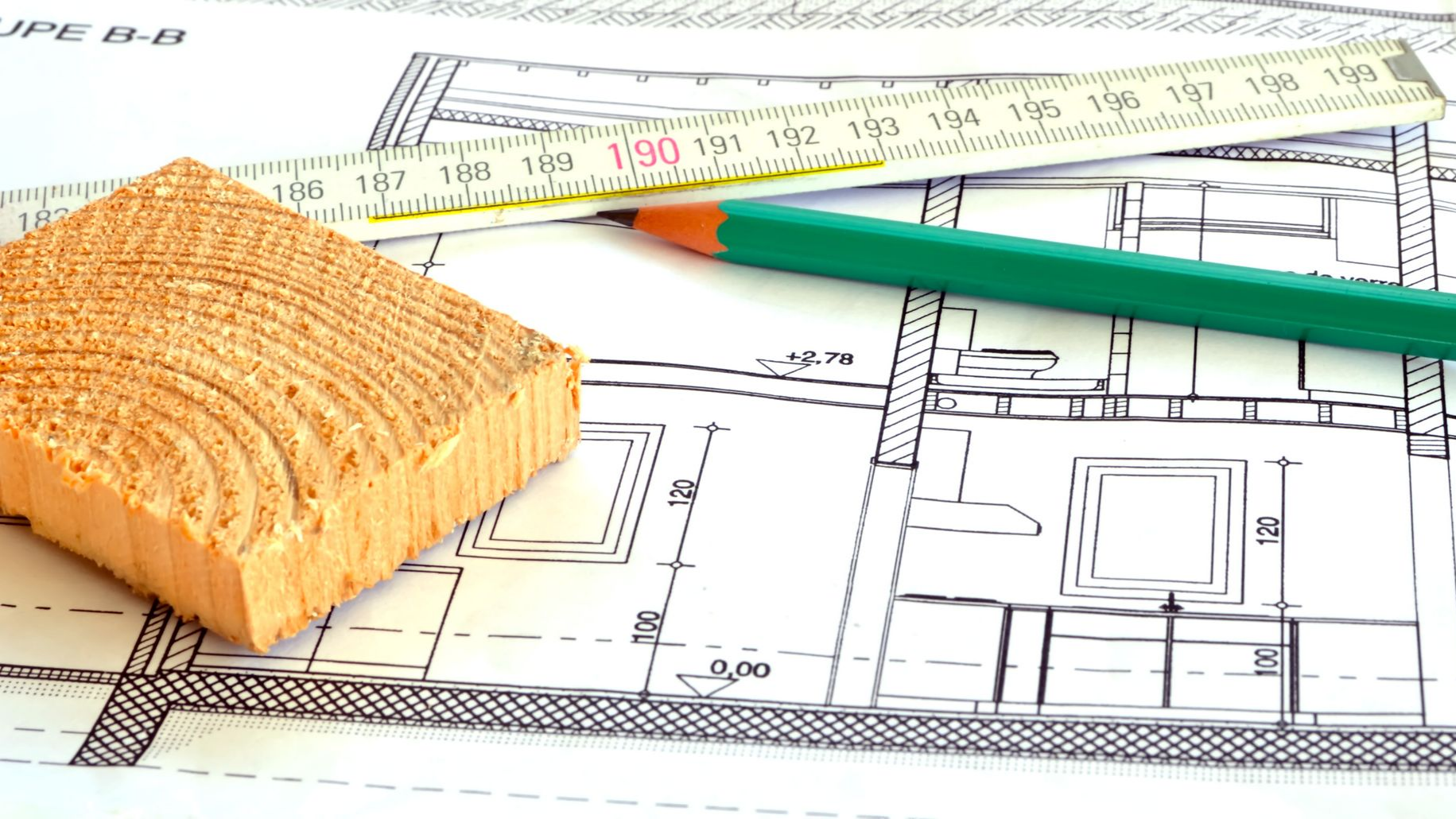 Plans d'architecture avec un bloc de bois, une règle et un crayon.