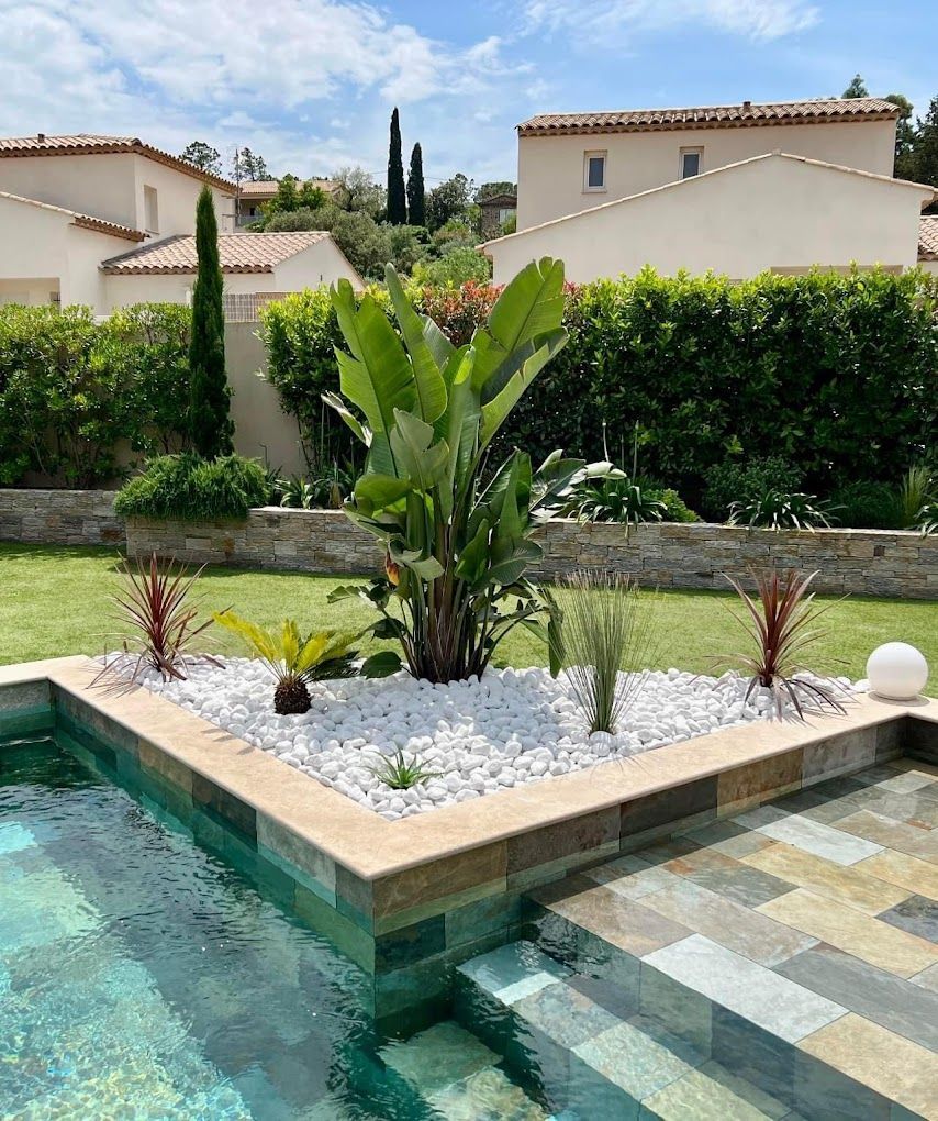Le coin d'une piscine décorée avec des galets et des bananiers
