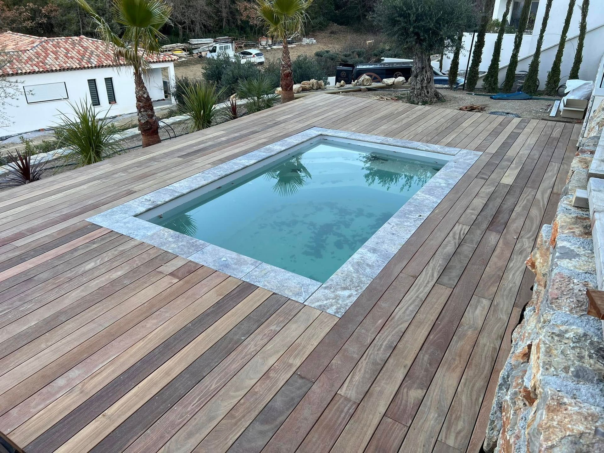 Une piscine bordée de pierres sur une terrasse en bois