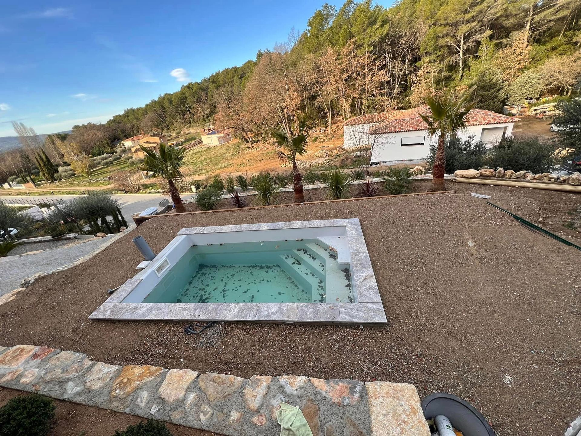 Une piscine au milieu d'un terrain en terre