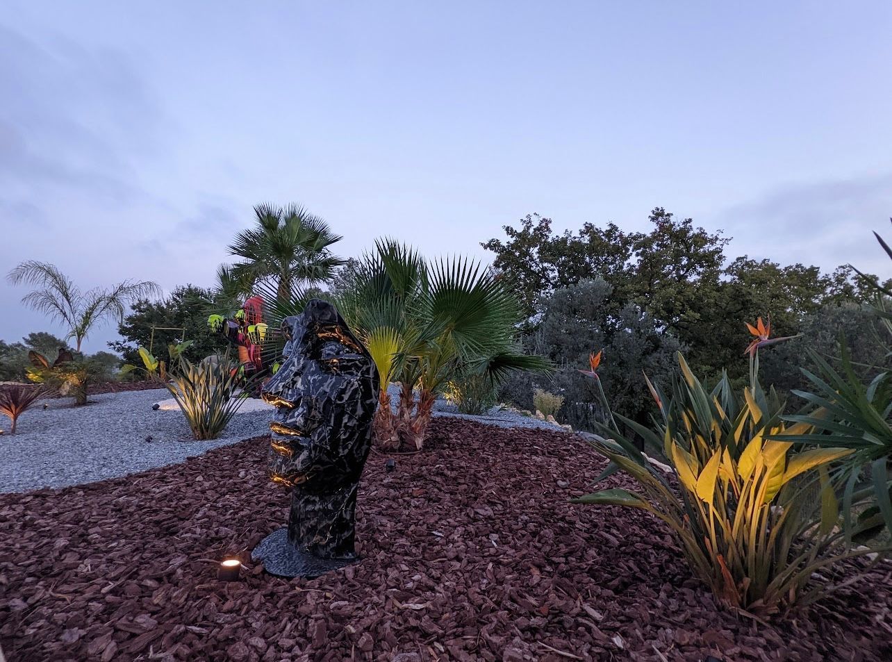 Des statues et massifs illuminés dans du paillage coloré