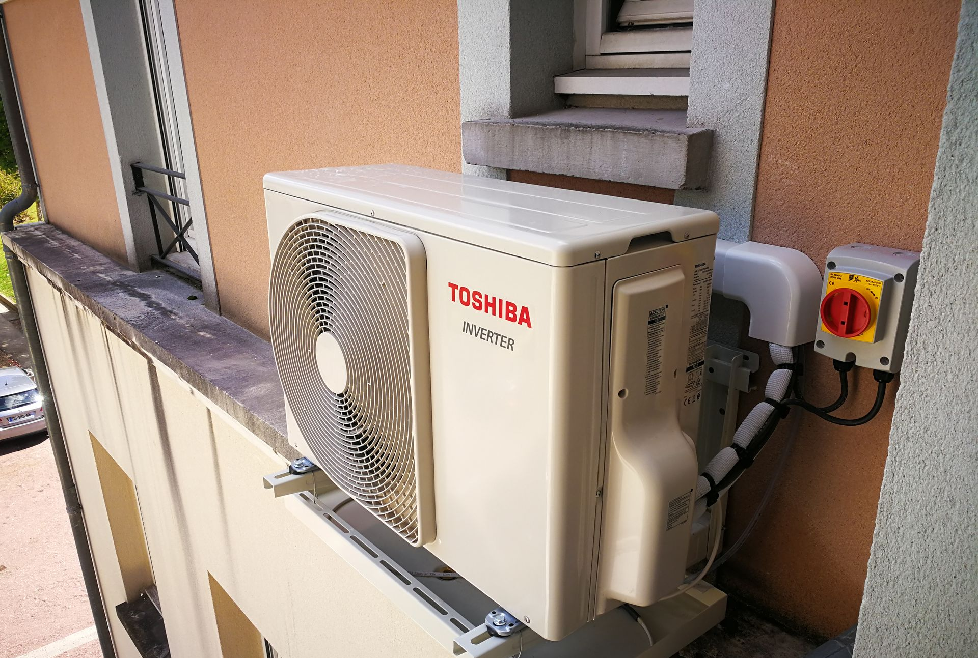 Unité de climatisation Toshiba montée sur la façade d'un bâtiment.