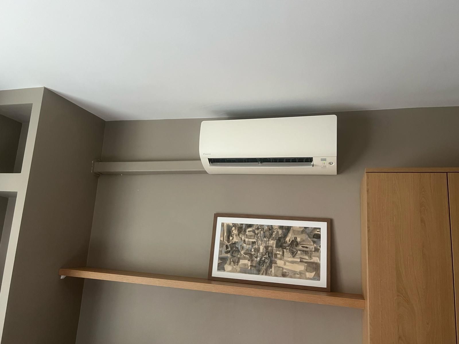 Unité de climatisation fixée sur un mur brun clair.