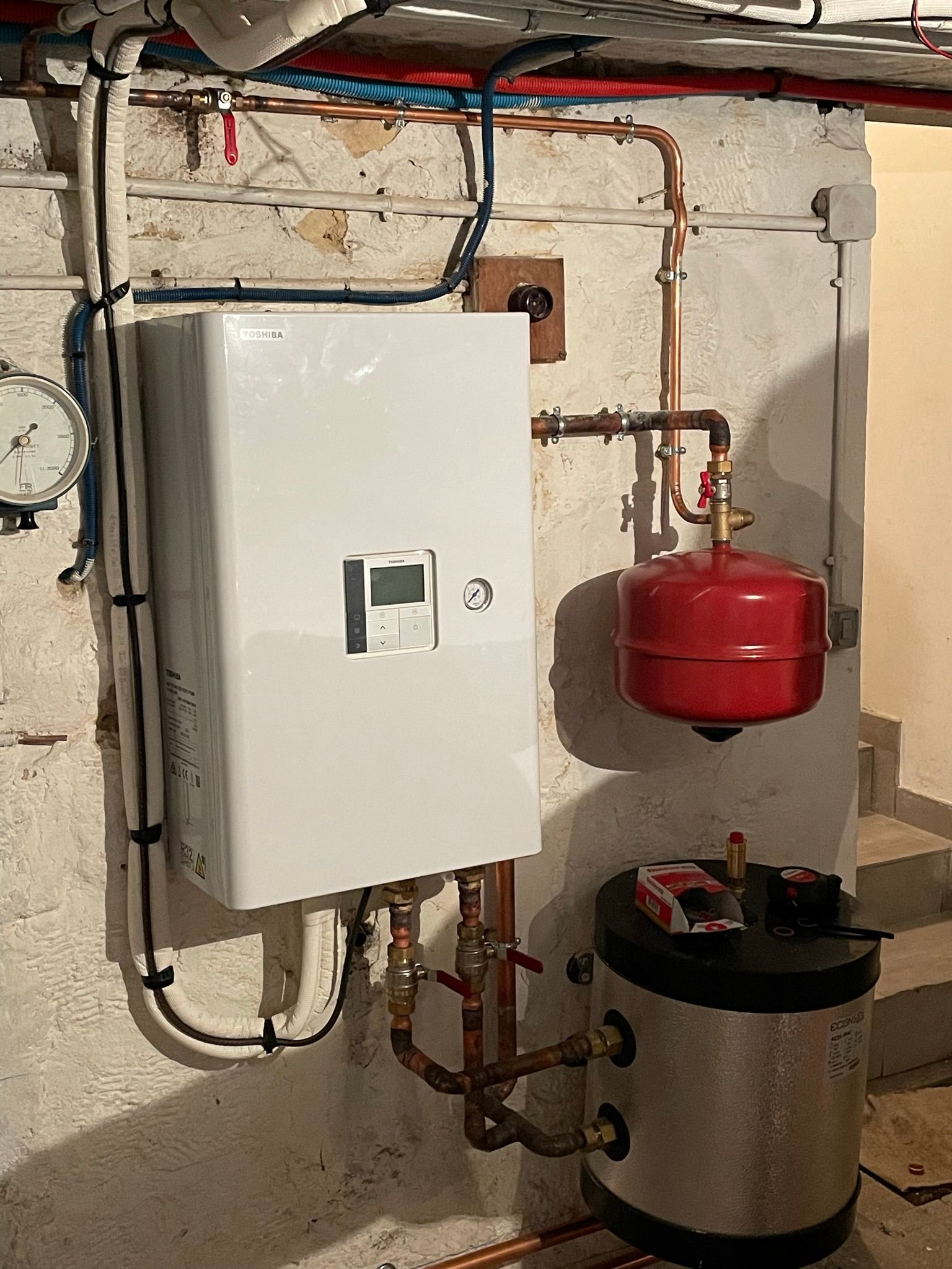 Chaudière murale blanche avec tuyaux en cuivre, vase d'expansion.