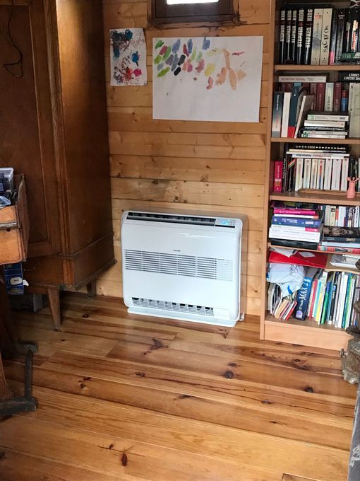 Intérieur aux murs en bois avec une climatisation, des étagères et un parquet.