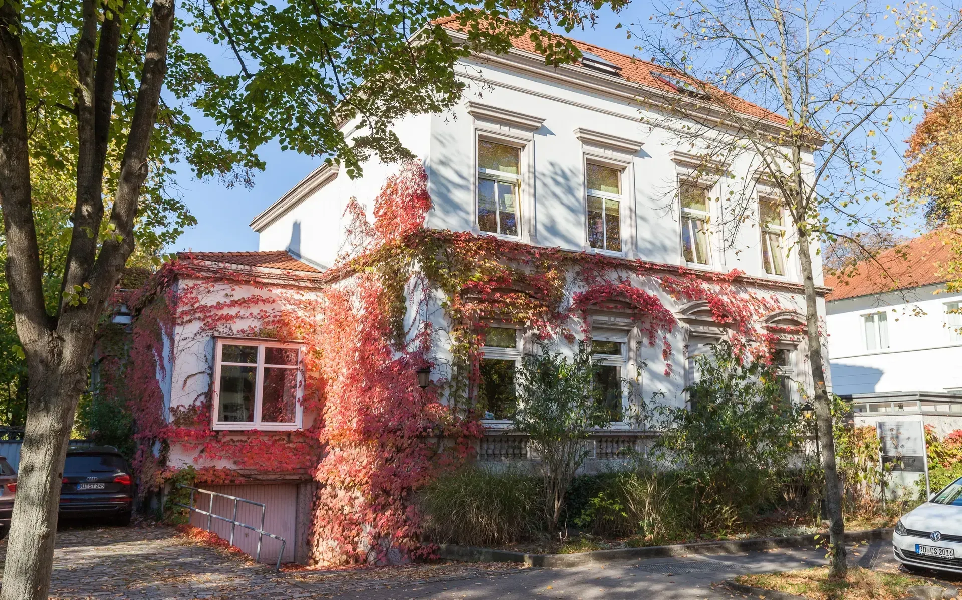 Ein weißes Haus einer Kanzlei mit rotem Efeu an der Seite