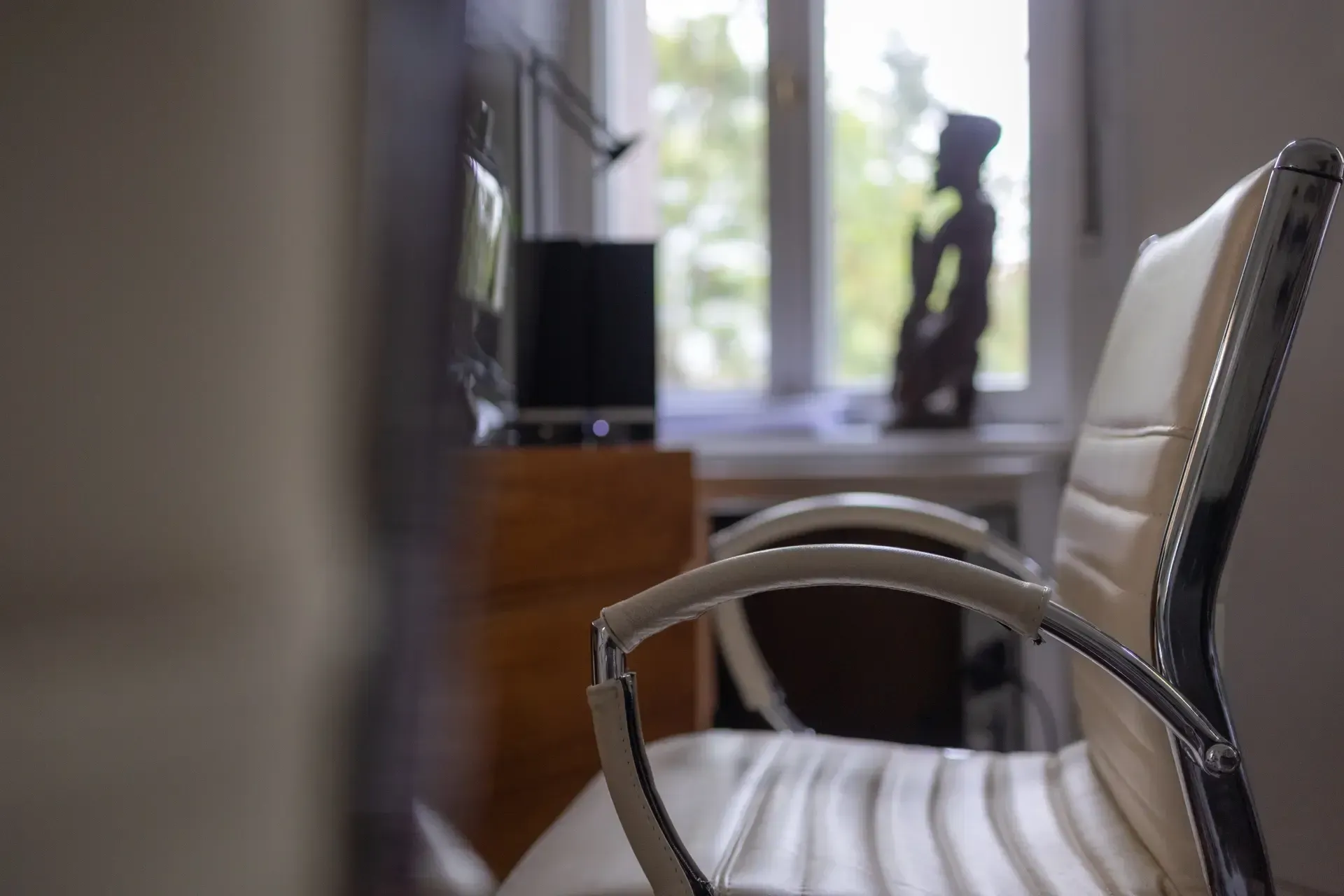 Ein weißer Bürostuhl steht vor einem Fenster in einem Zimmer einer Kanzlei.