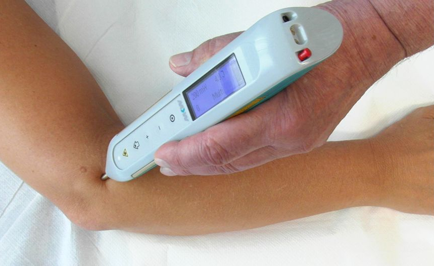Hand hält ein weißes Laserakupunkturgerät mit violetter Anzeige