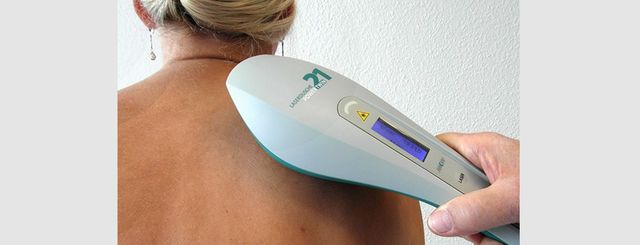 Lasertherapie – Lasergerät, das den oberen Rücken/die Schulter einer Person in einer klinischen Umgebung scannt