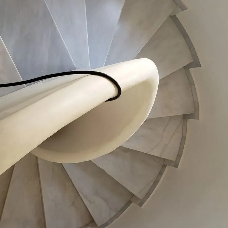 Un primer plano de una escalera de caracol con una barandilla blanca.