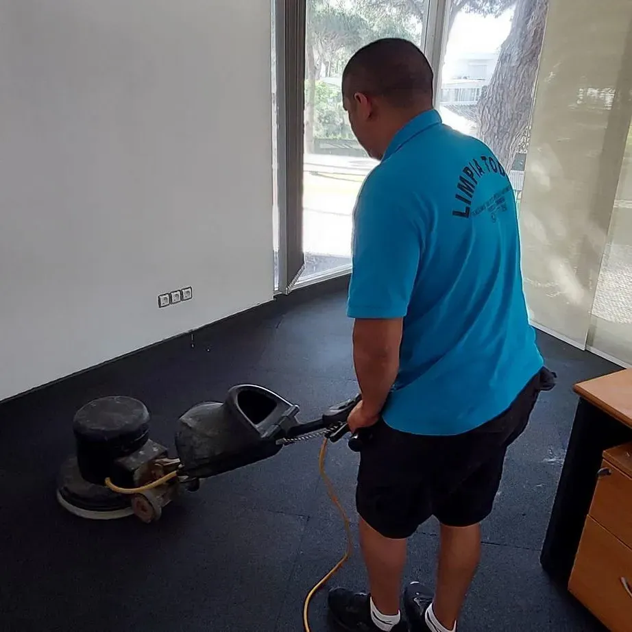Un hombre con una camisa azul está usando una máquina para limpiar el piso.
