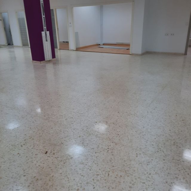 Una habitación grande con suelo blanco y columnas moradas.