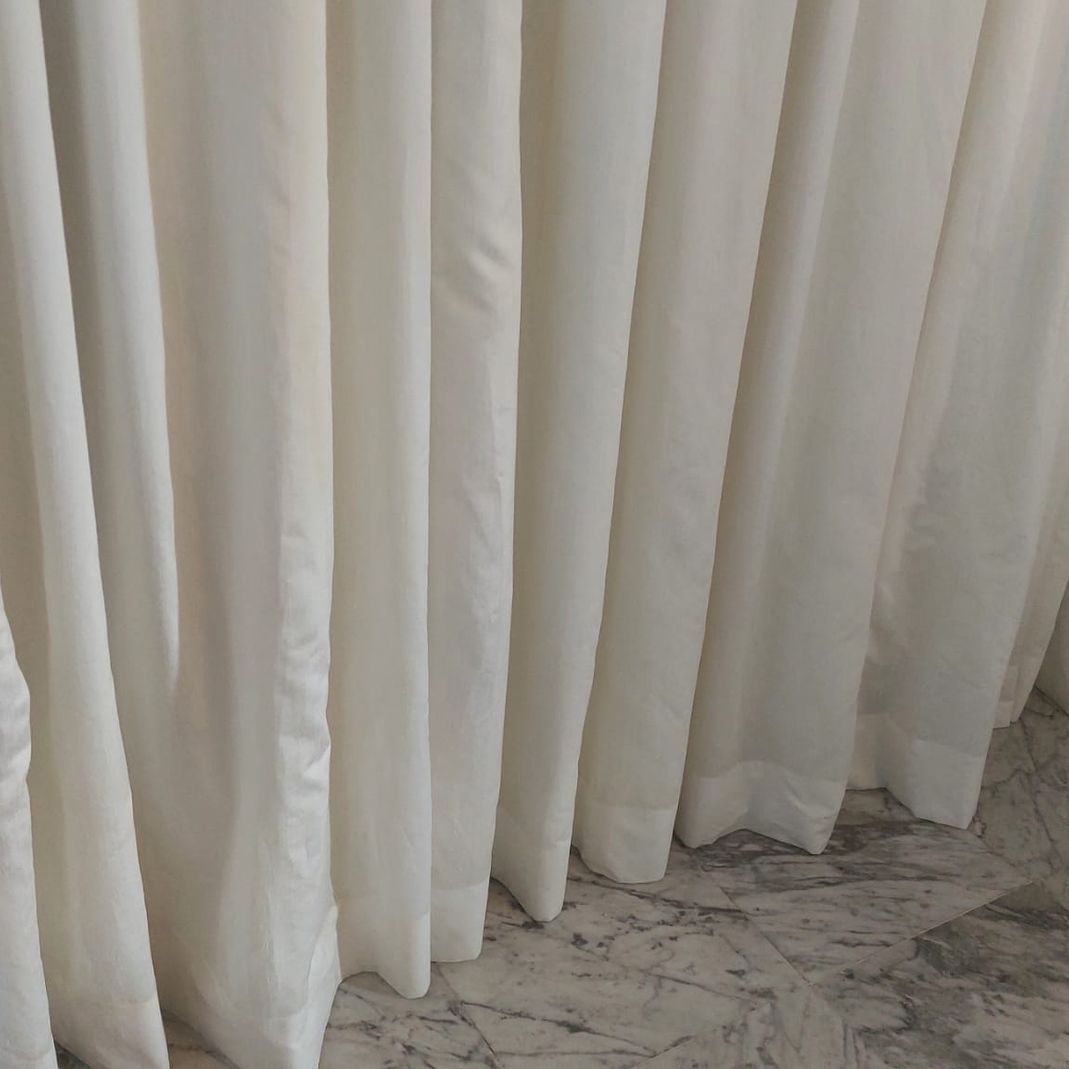 Un primer plano de cortinas blancas sobre un suelo de mármol.