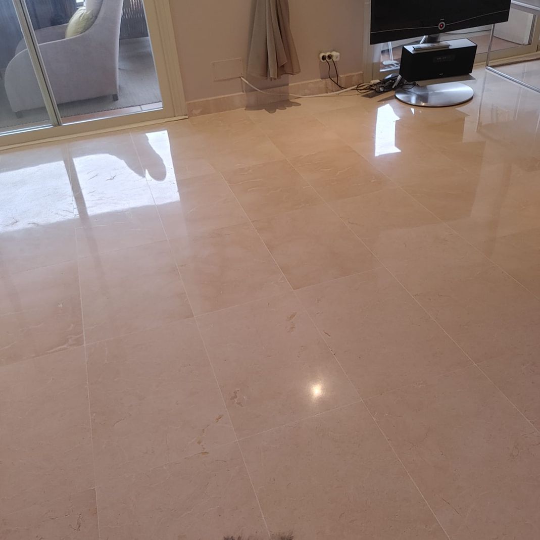 Una sala de estar con suelo de mármol y un televisor sobre un soporte.