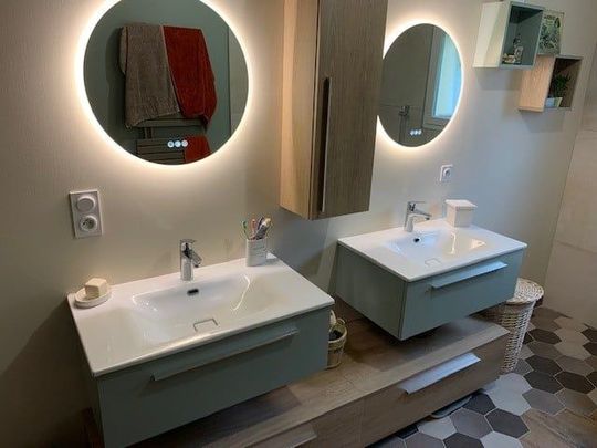 Salle de bains moderne avec deux miroirs éclairés, double vasque et meubles en bois et bleus.