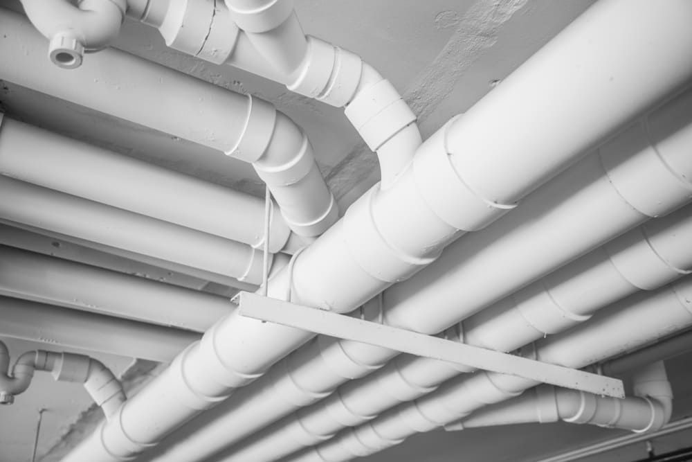 Tuyaux et conduits de plafond peints en blanc traversant un plafond industriel