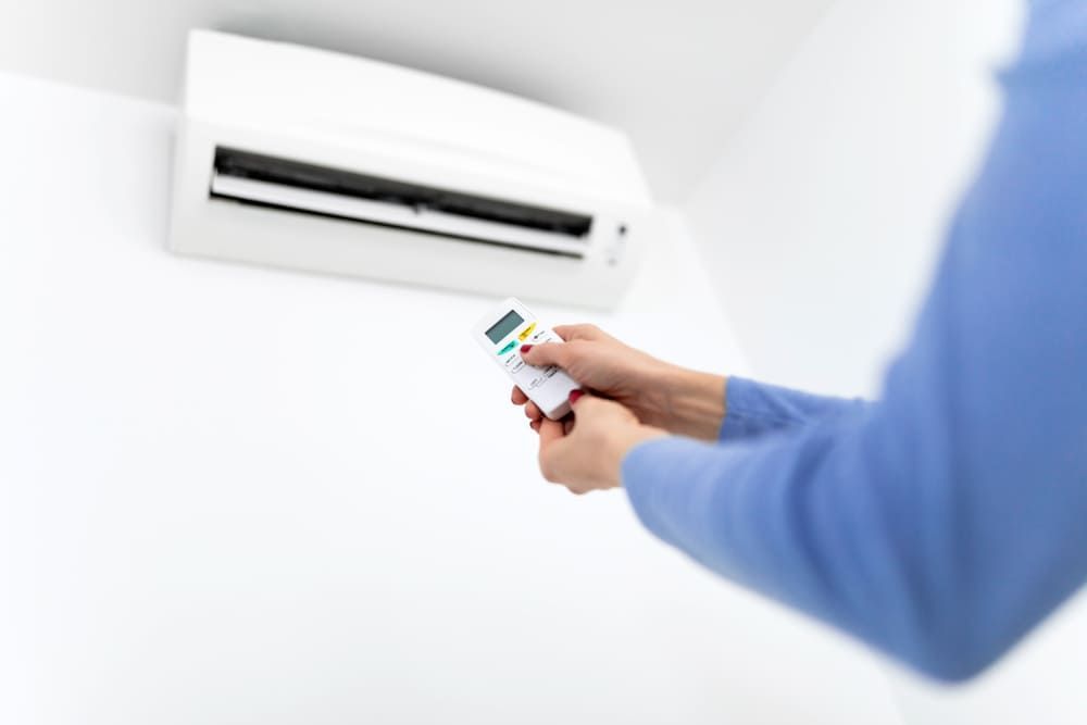Personne utilisant une télécommande pour contrôler un climatiseur mural