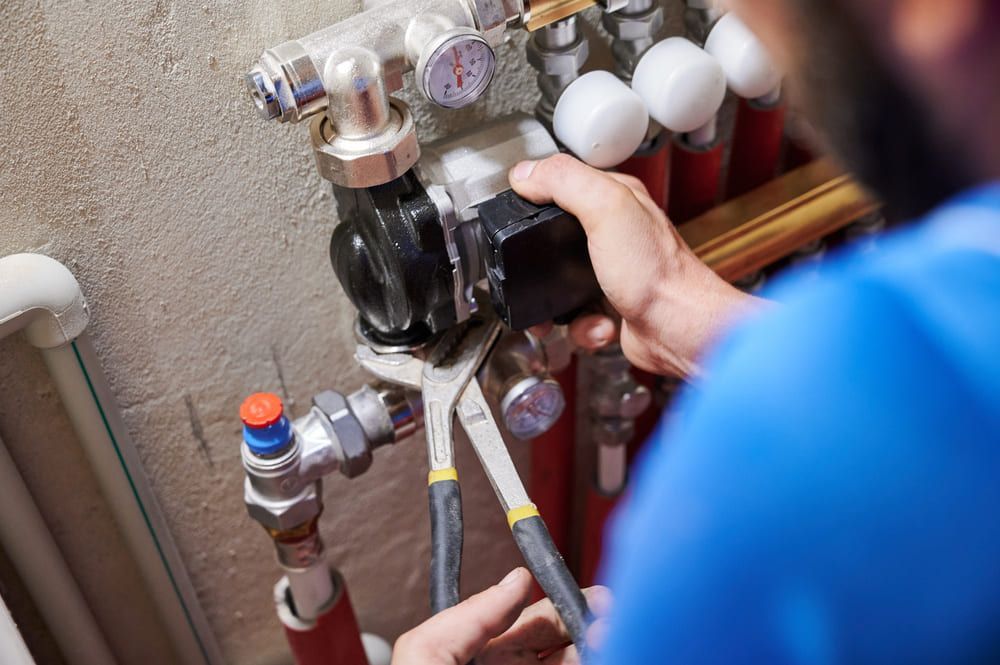 Technicien ajustant les tuyaux et les vannes d'un compteur d'eau à l'intérieur