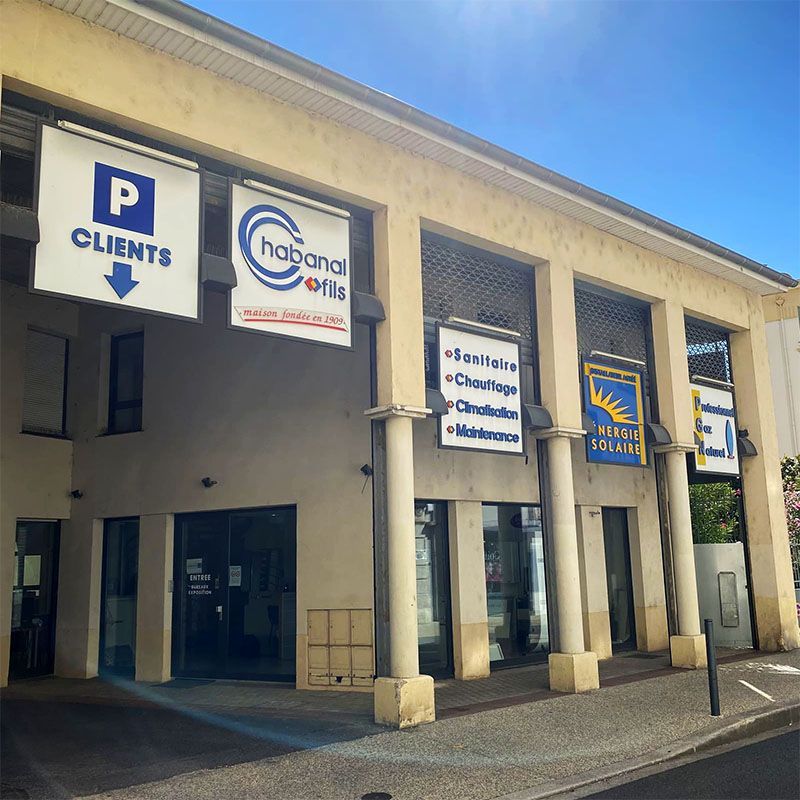 Façades commerciales couvertes avec enseignes et places de parking sous un ciel bleu