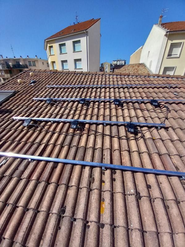 Toit-terrasse recouvert de tuiles en terre cuite et de plusieurs tuyaux bleus, avec des immeubles d'appartements en arrière-plan.