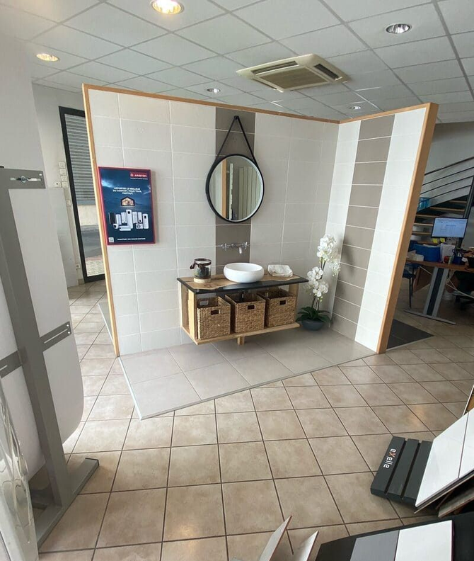 Petite salle de bains carrelée avec un meuble-lavabo blanc, un miroir rond et une cloison en bois.