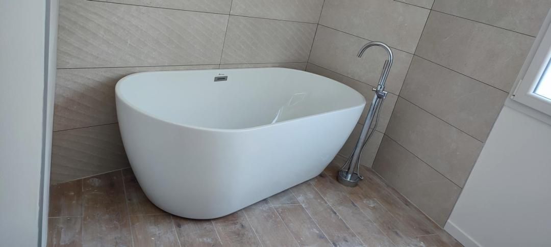 Salle de bains moderne avec baignoire îlot blanche, mur carrelé et robinet sur pied