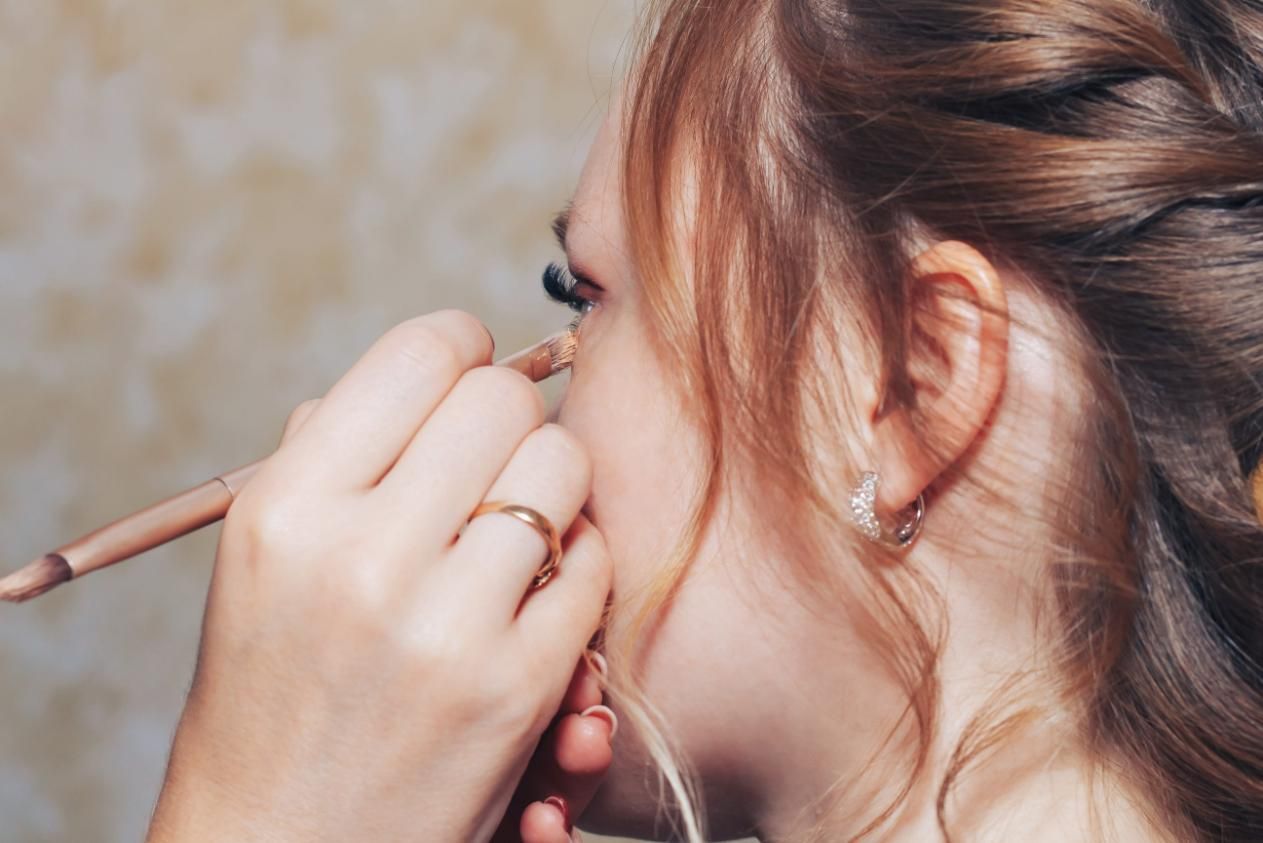 Persona aplicándose maquillaje de ojos con una brocha en primer plano.