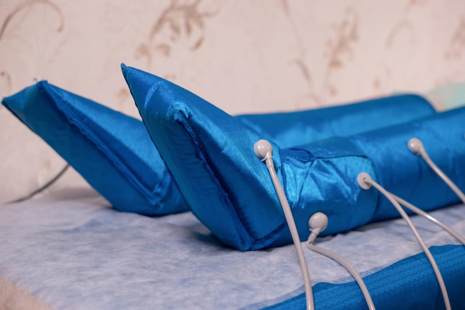 Dispositivo acolchado azul con cables sensores blancos sobre una mesa, mostrado en primer plano.