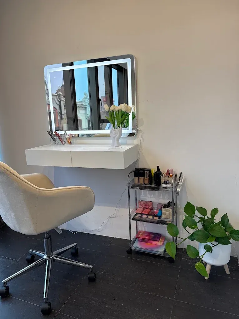 Tocador minimalista con espejo, taburete y planta en un salón de belleza moderno o en un espacio de belleza doméstico.