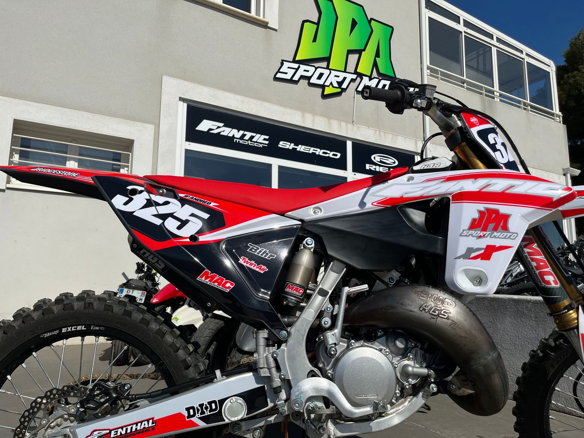 Moto cross rouge devant l'enseigne