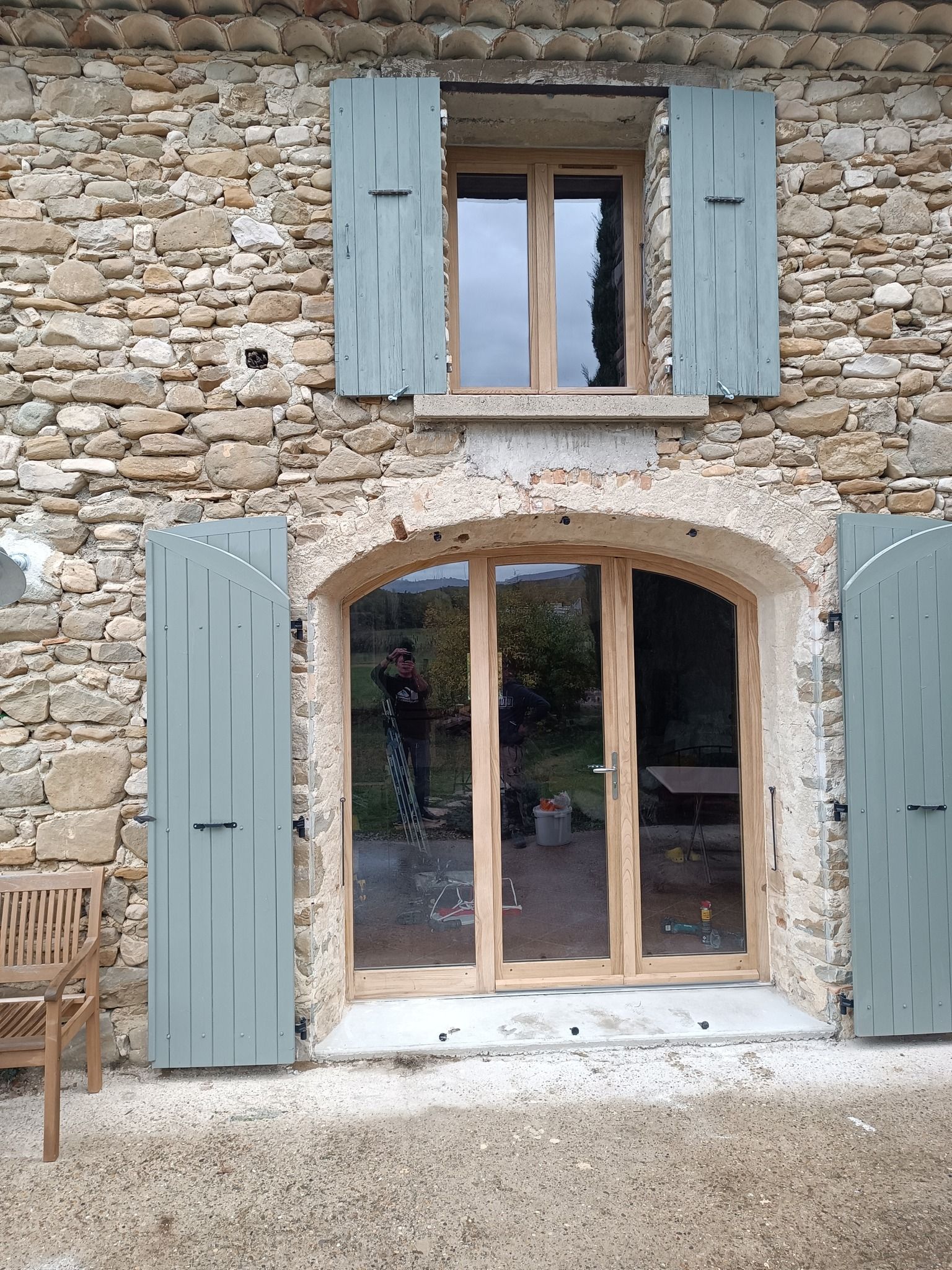 Fenêtres avec contour en bois, volets en bois vert pâle, maison en pierre